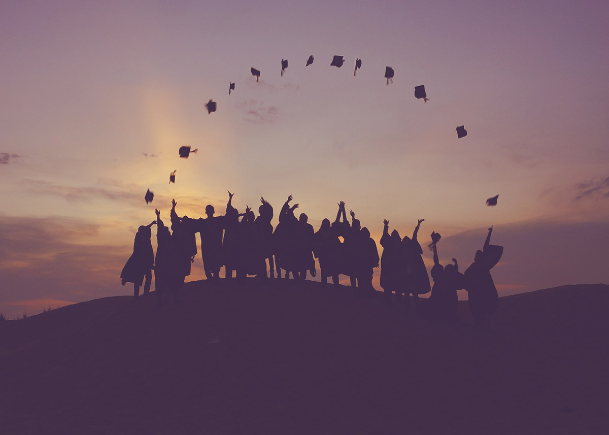 group of graduates throwing their caps in the air