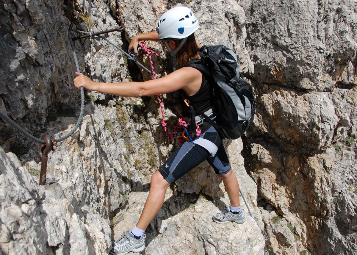 person climbing mountain with helmet and gear