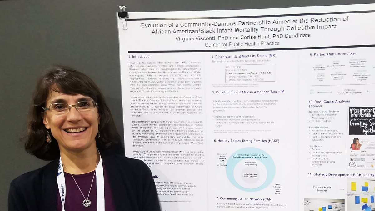 faculty member smiling standing next to her research poster
