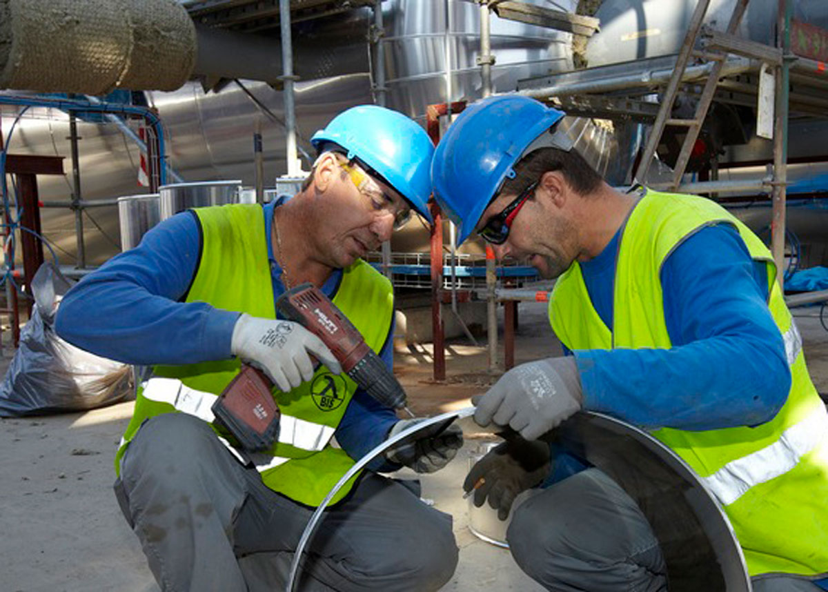 two workers in hard hats and goggles drilling