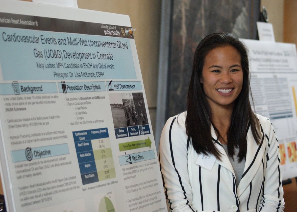 student standing in front of her poster at Research Day