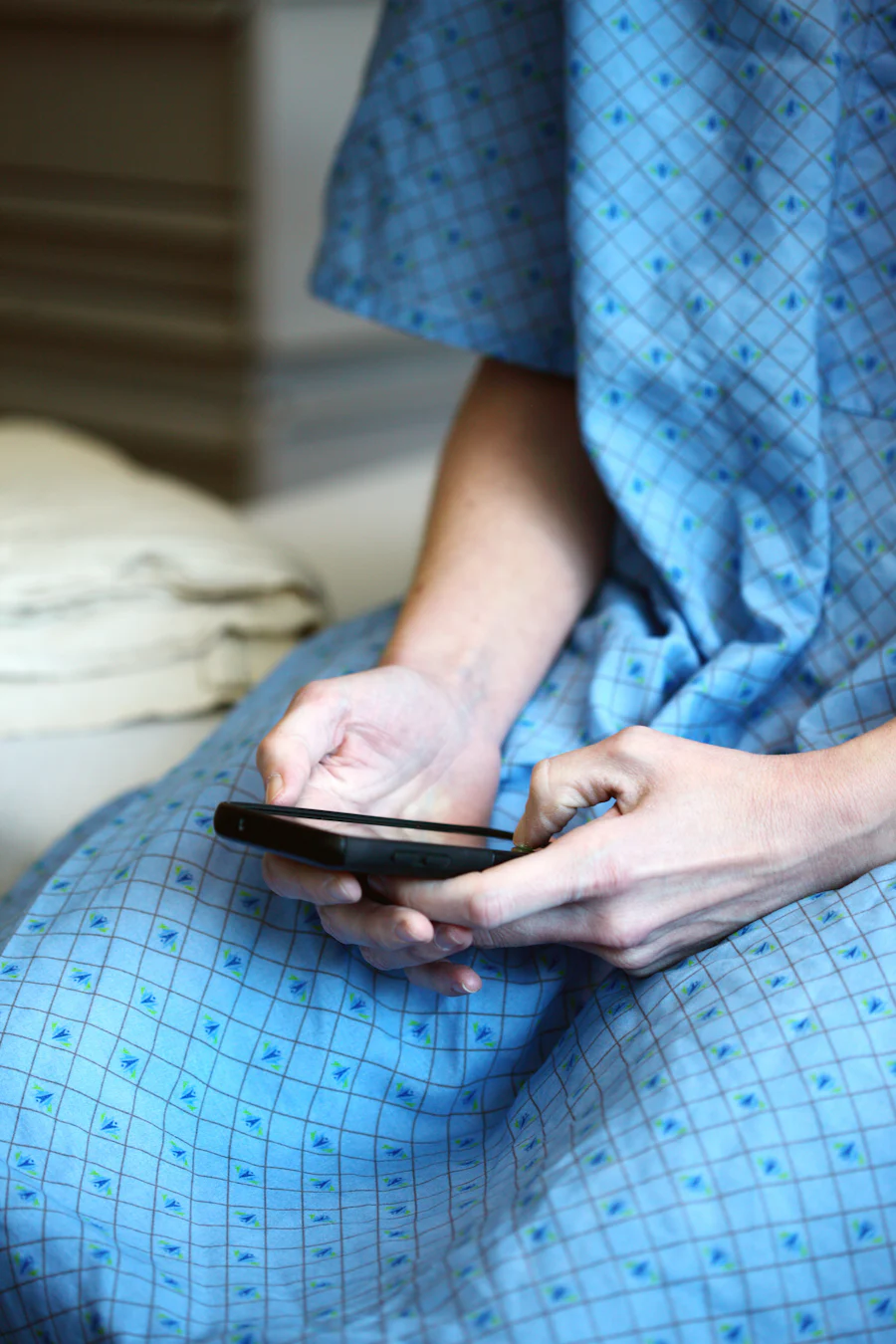 Photo of hospital patient in a gown on their phone
