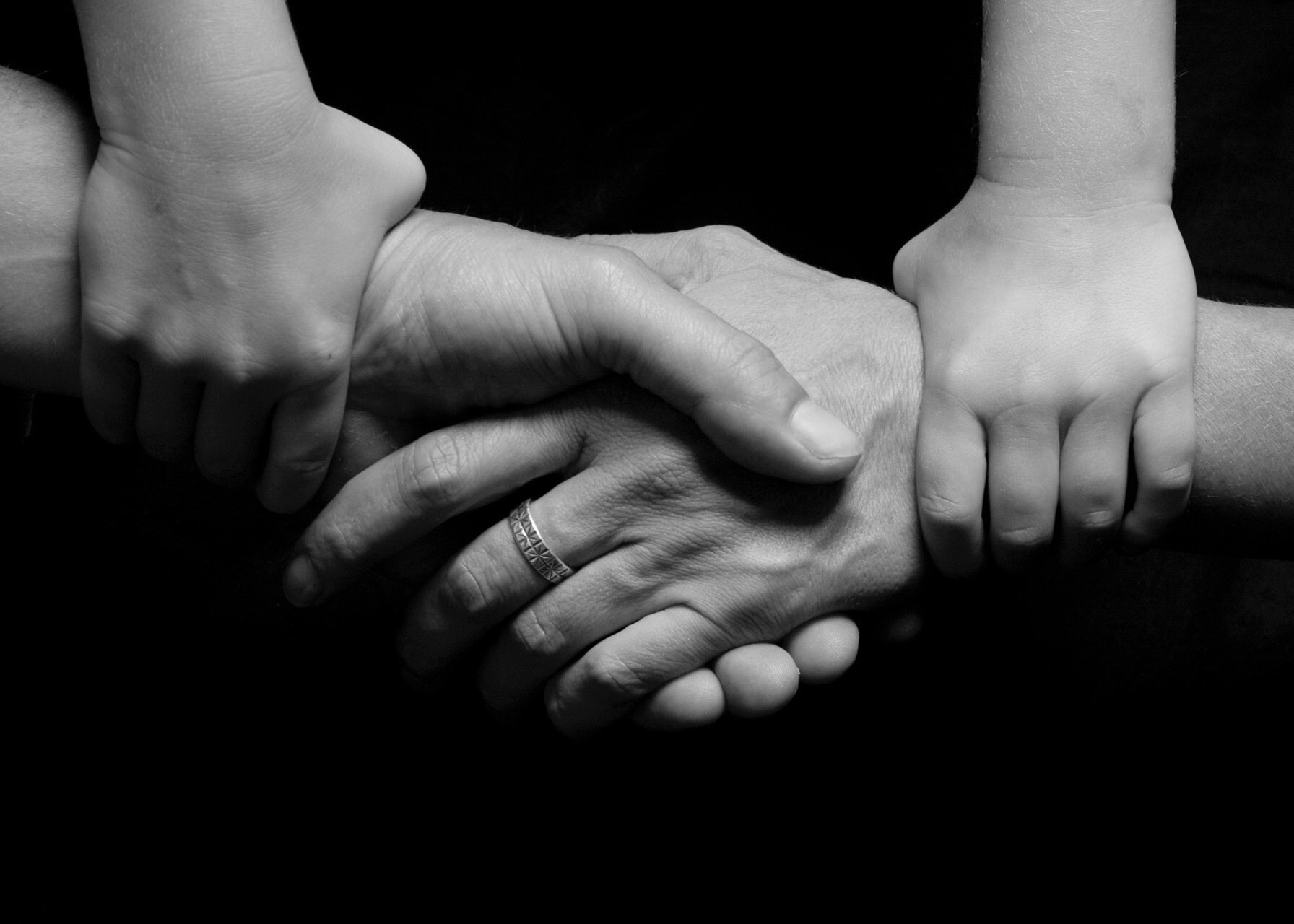 Two hands shaking with child's hand gripping each wrist