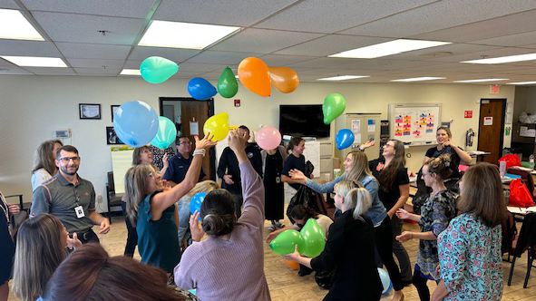 Group of adults in a classroom trying to keep balloons in the air