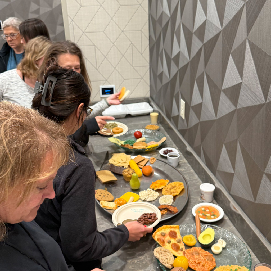 People choosing different fake food items to fill their plates