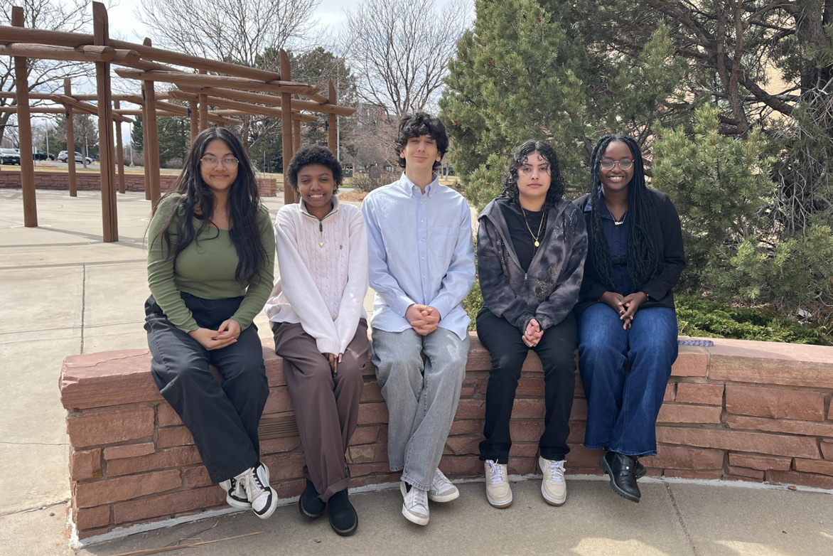 Five young people sitting on red stone bench