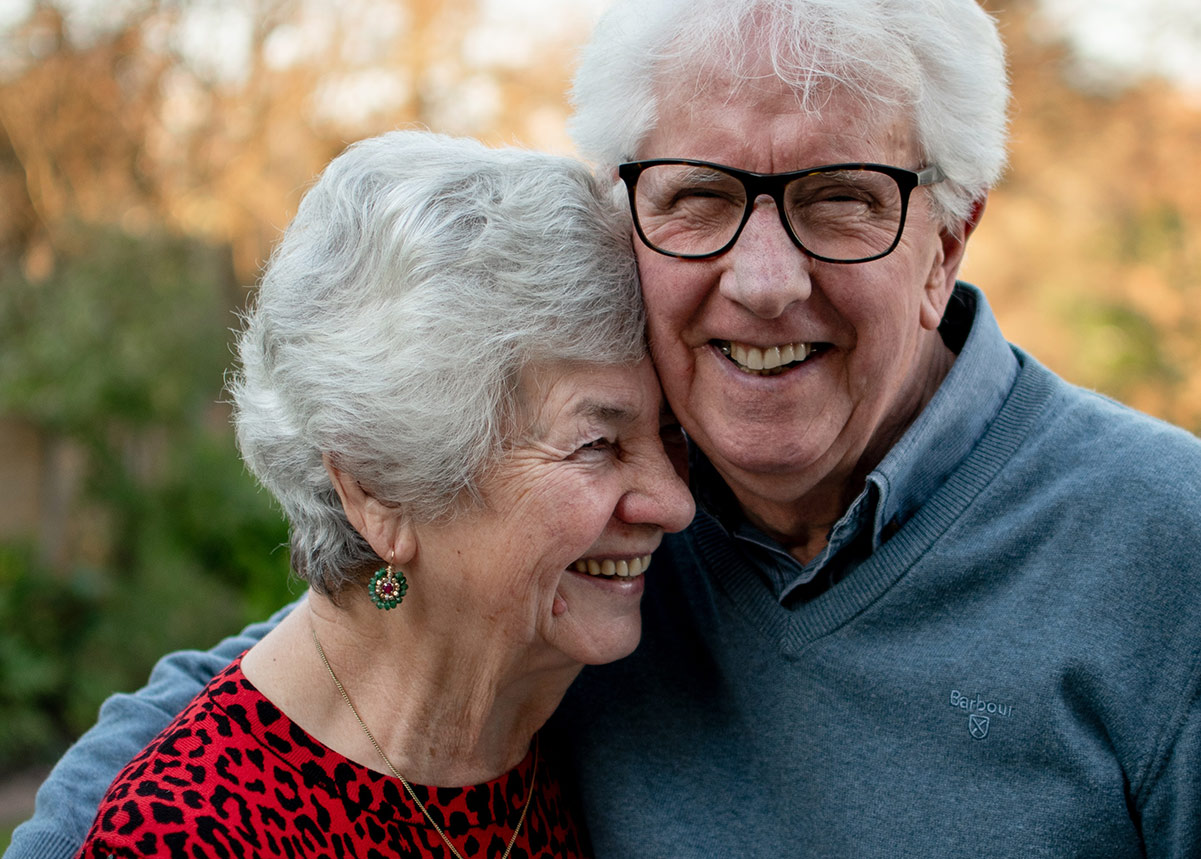 an older adult couple embracing and smiling