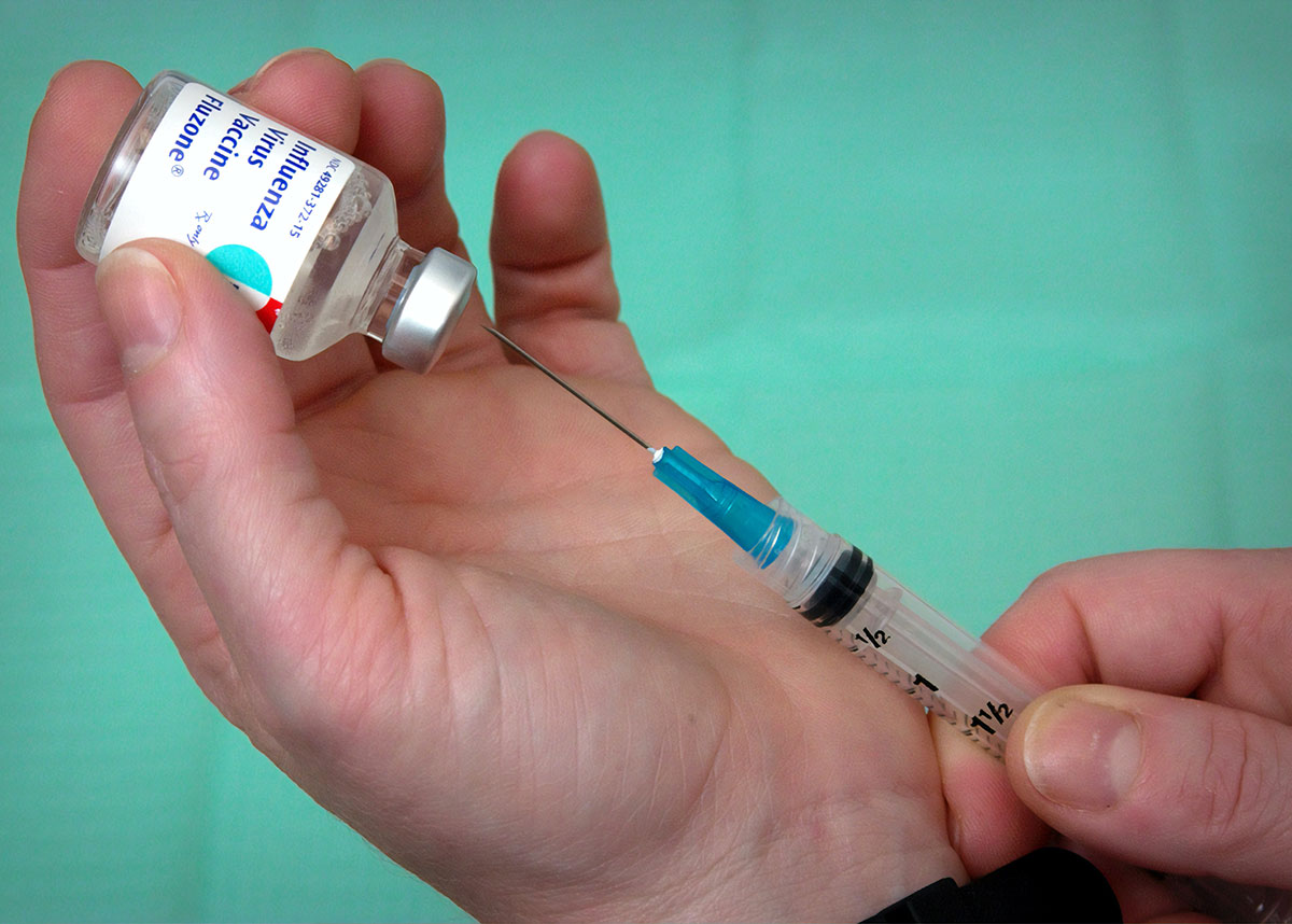 Image of hand holding and pulling a vaccination out of a bottle