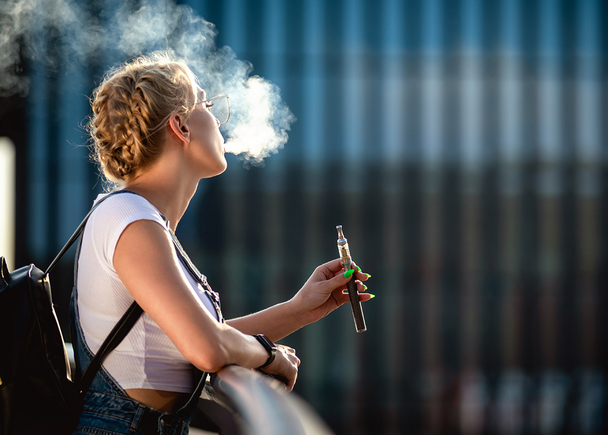 woman blowing smoke from vape pen