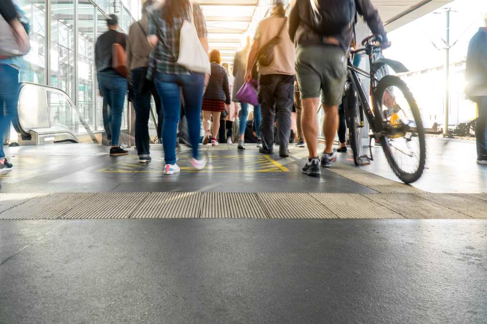 A city street or transit hub and a group of people in casual clothing walking away from the camera.