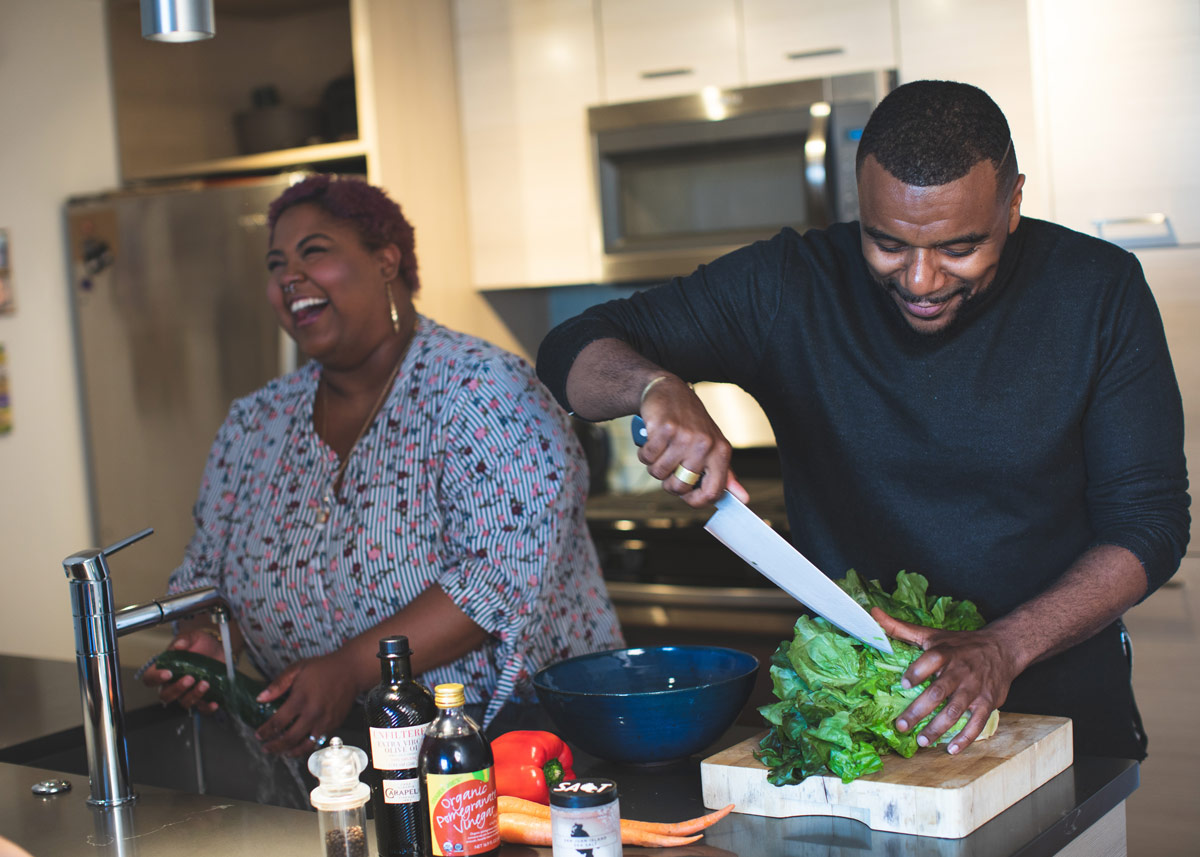 two people laughing and cooking together
