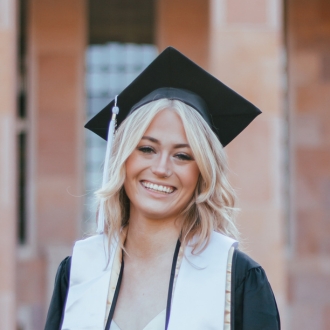 Woman in headshot wearing graduation cap smiling