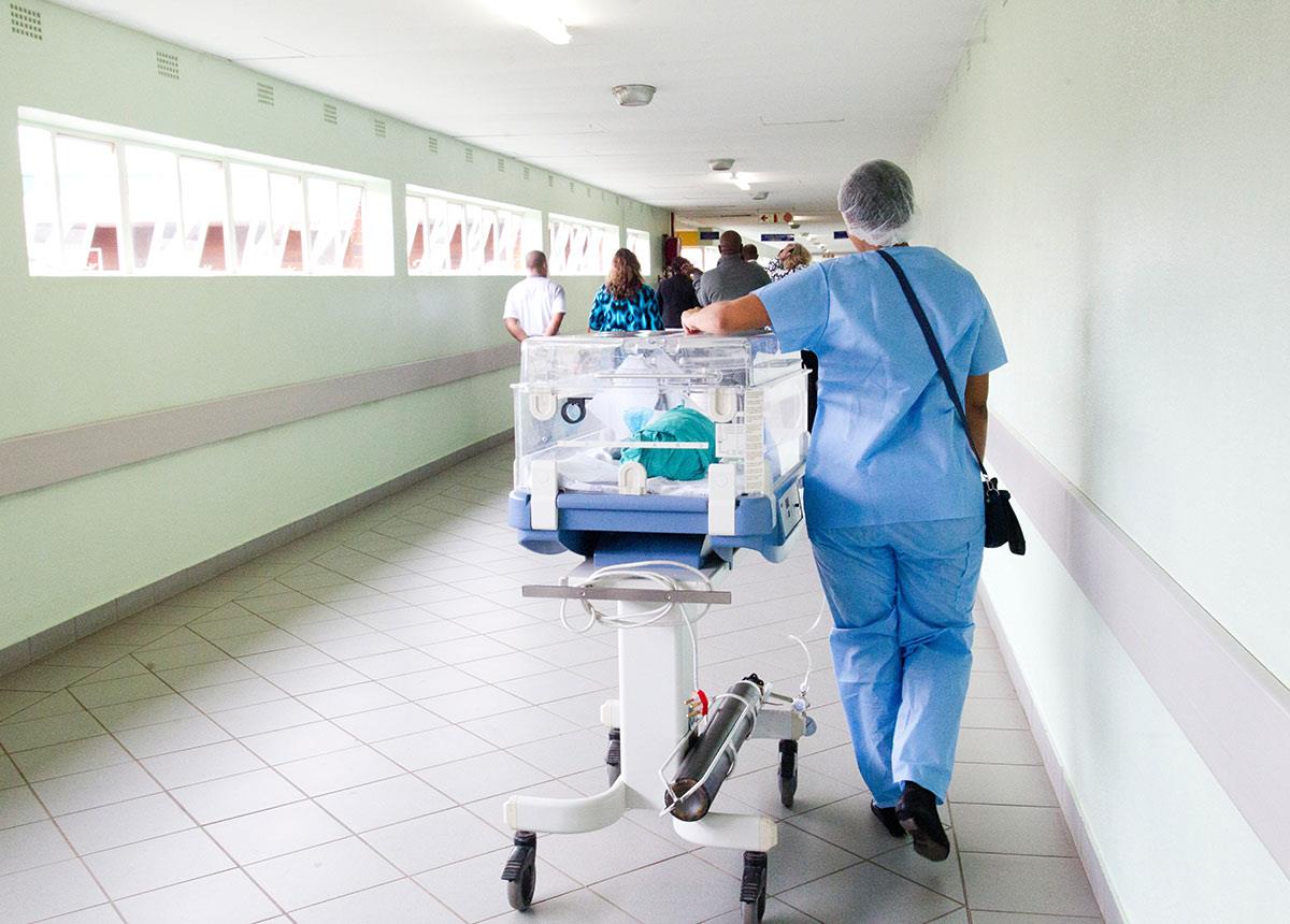 healthcare worker pushing a gurney down a hospital hallway