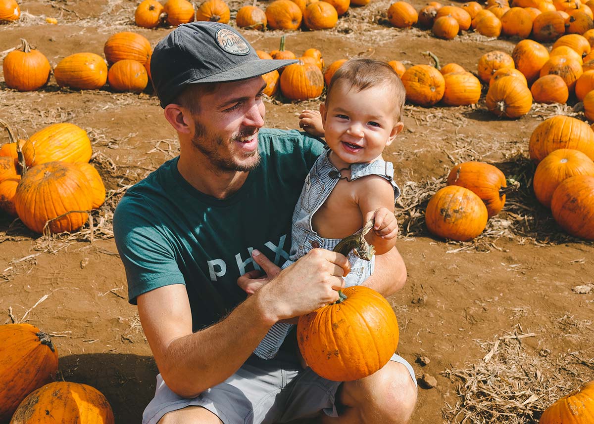man and child smiling in pumpkin patch