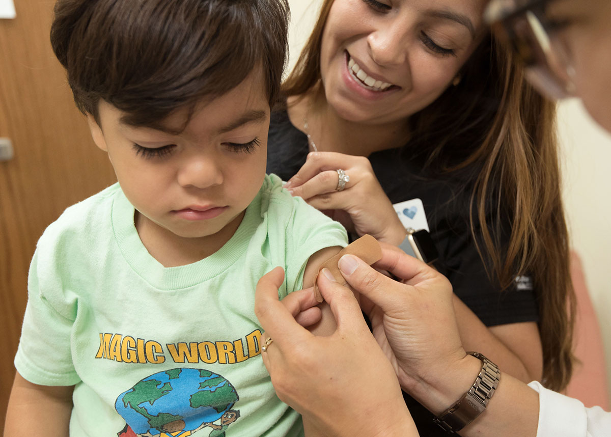Healthcare worker putting a bandaid on a child who received a vaccine