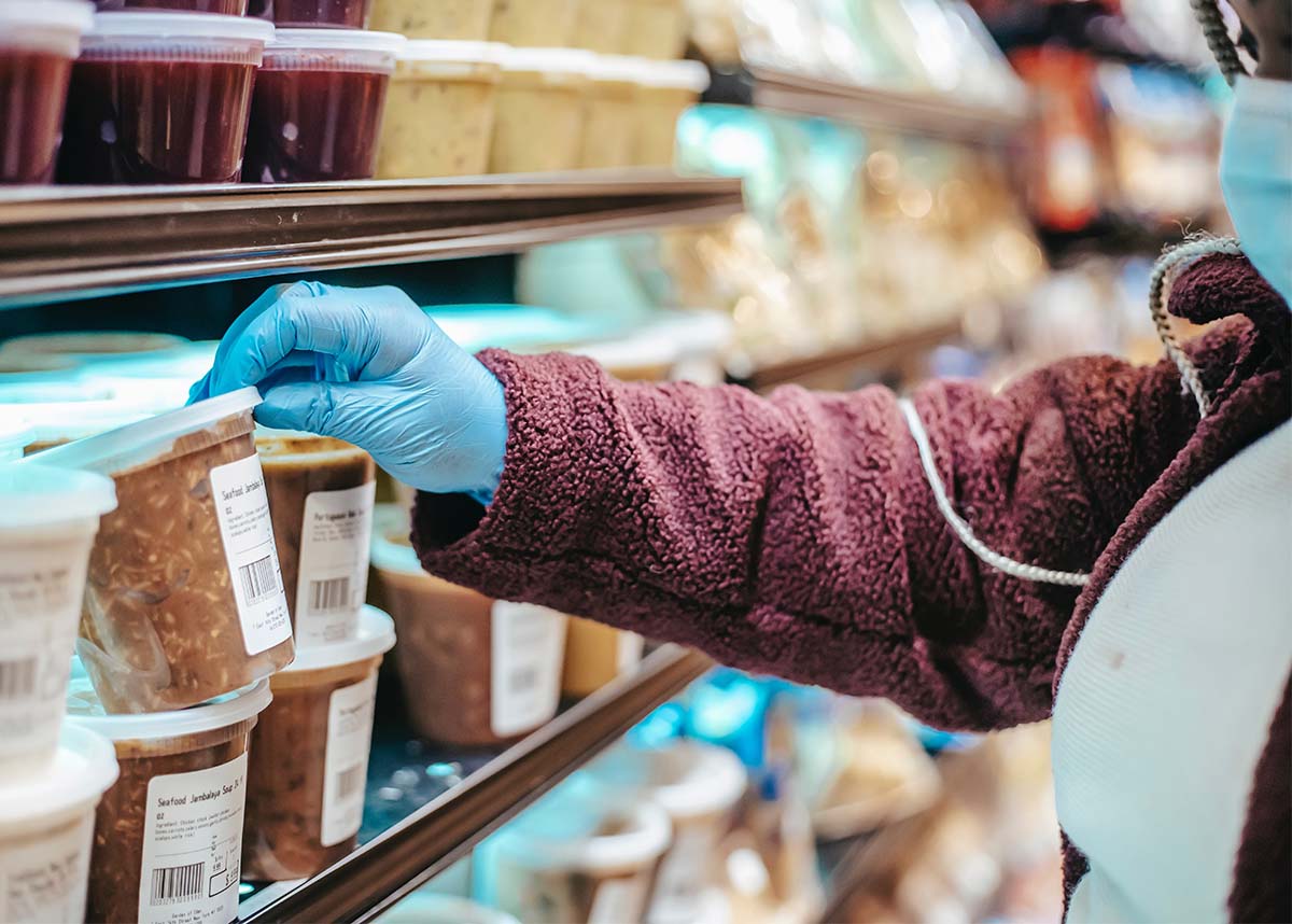 person grabbing container of soup from a shelf