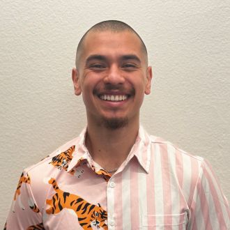 Headshot of man wearing pink striped shirt with tigers