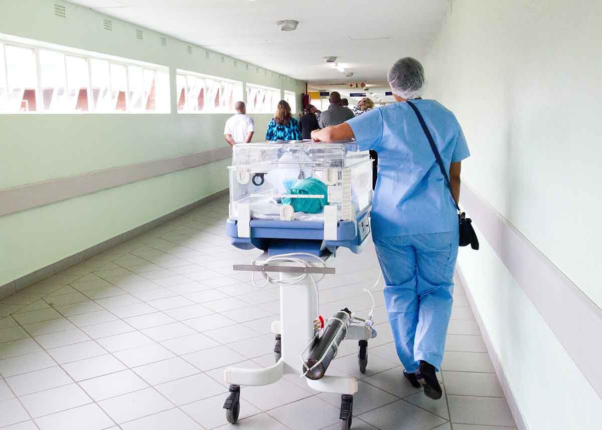 Healthcare worker rolling a stretcher inside a hospital
