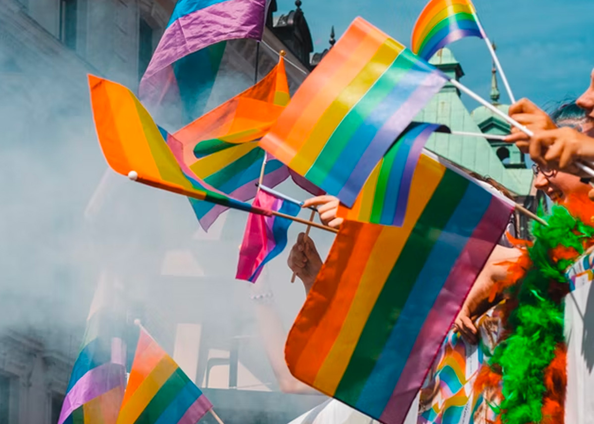 Close up of multiple rainbow pride flags being held in air