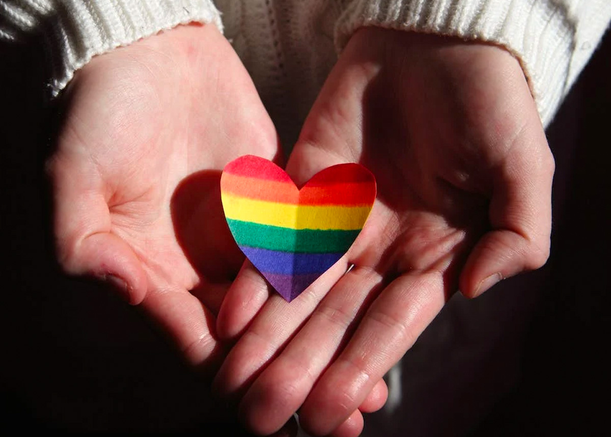 Hands holding rainbow colored heart
