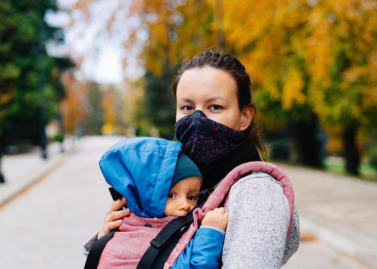 Mother wearing a mask outdoors holding infant