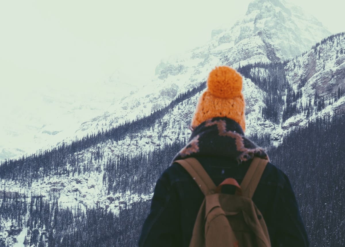person in orange hat staring at mountain