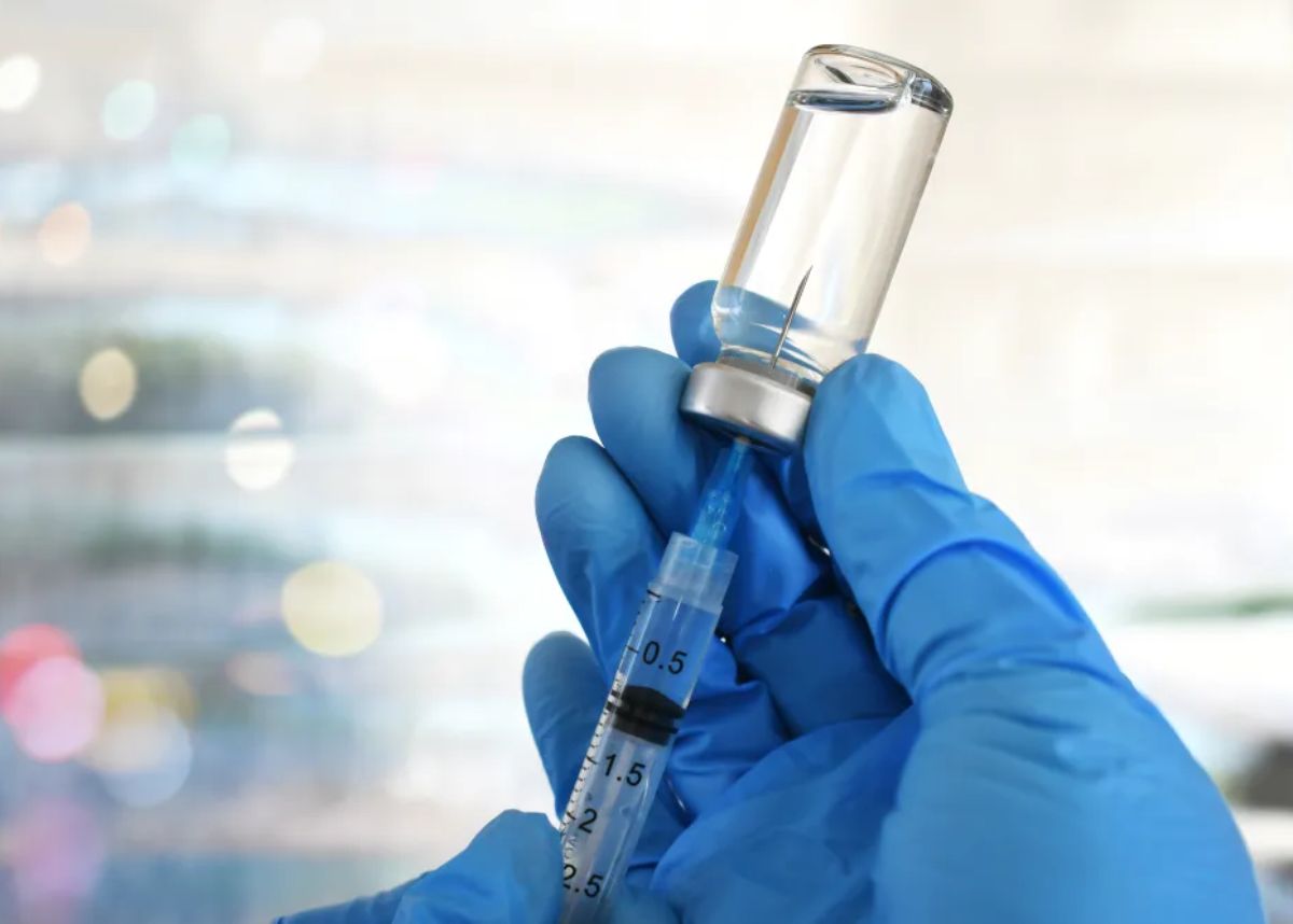 stock image of needle inserting into vaccine bottle