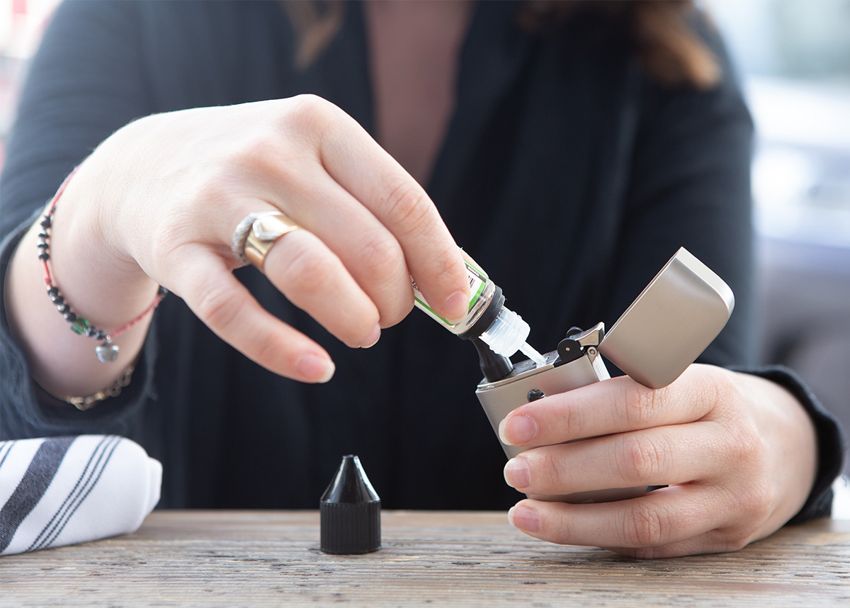 person filling reusable vape with nicotine liquid