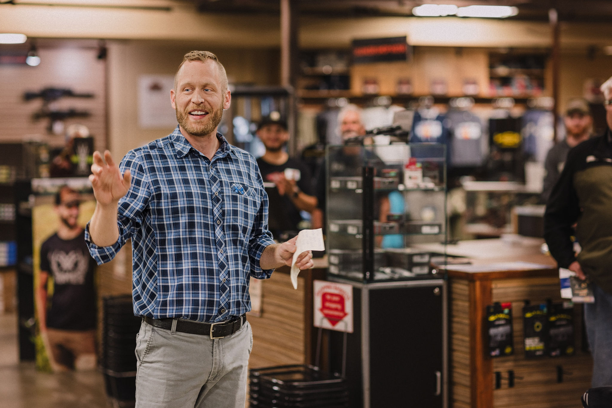 man standing talking to a group of people in a gun store