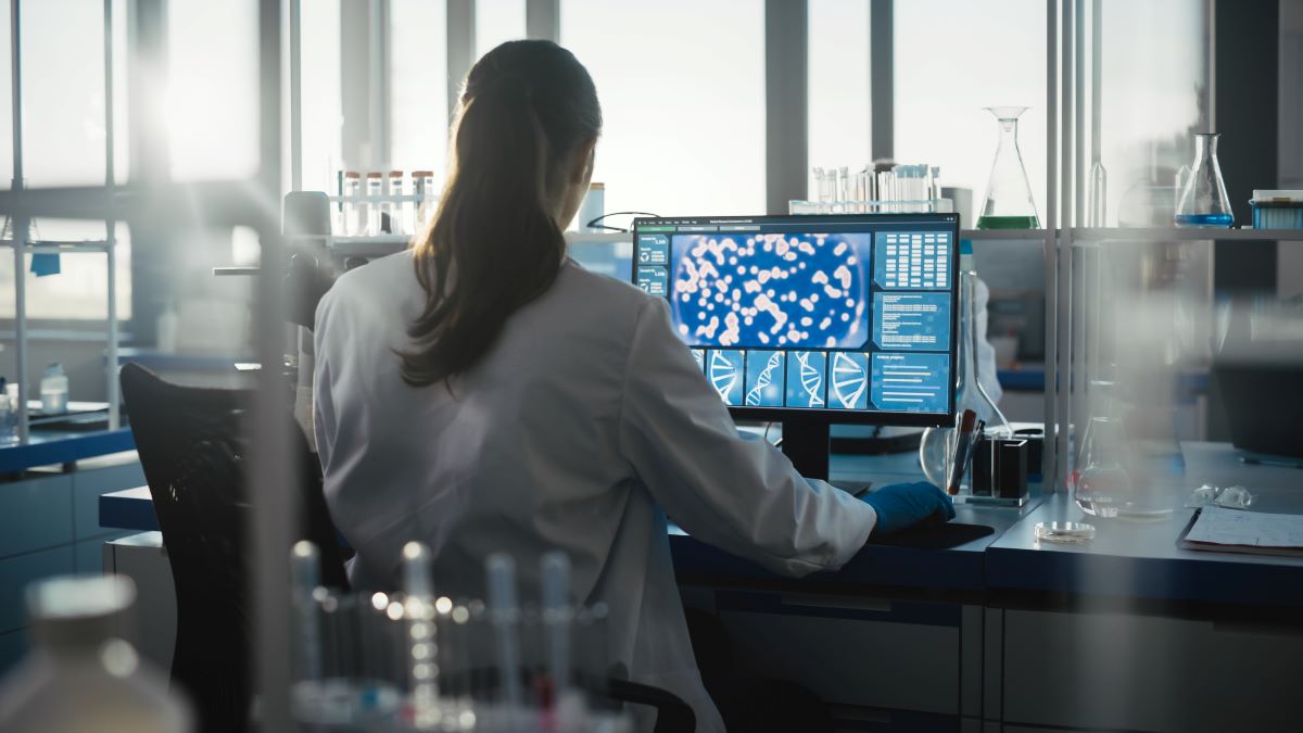 Medical Science Laboratory with Diverse Team of Professional Biotechnology Scientists Developing Drugs, Female Biochemist Working on Computer Showing Gene Therapy Interface.