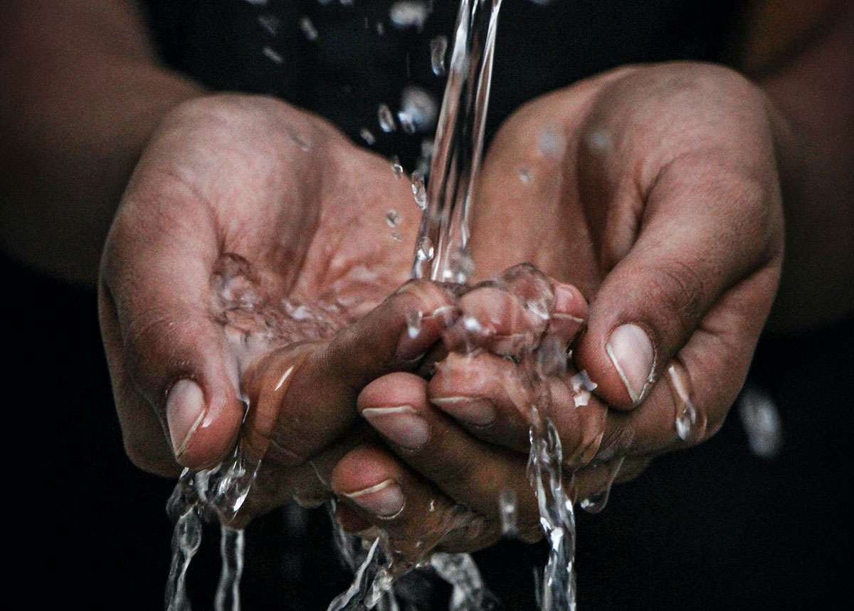 water running over person's cupped hands