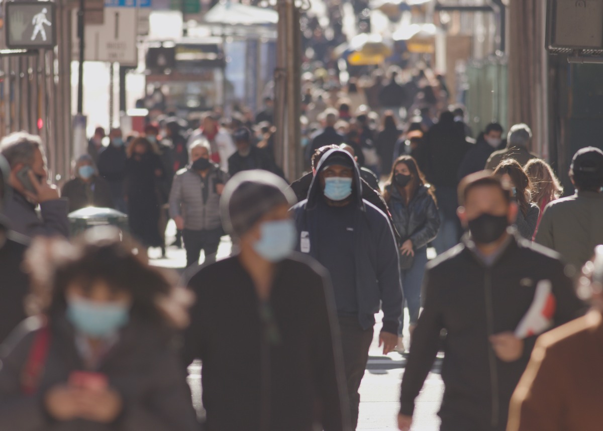 Crowd of people walking street wearing masks during COVID 19 pandemic