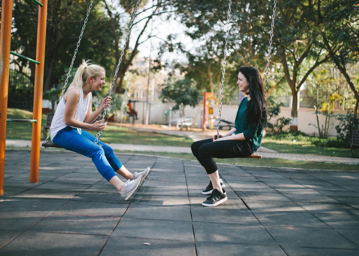 two people swinging on a playground swing